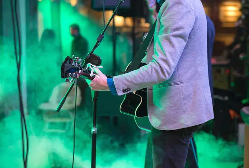 Musician playing guitar on a smoky stage.