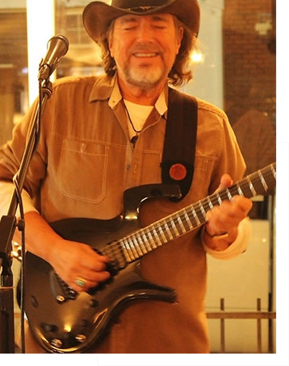 Man playing electric guitar with a strap indoors.
