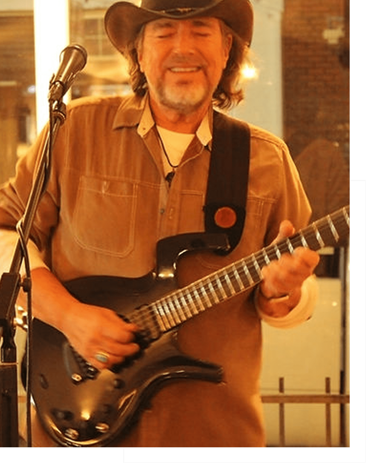 Man playing electric guitar with a strap indoors.