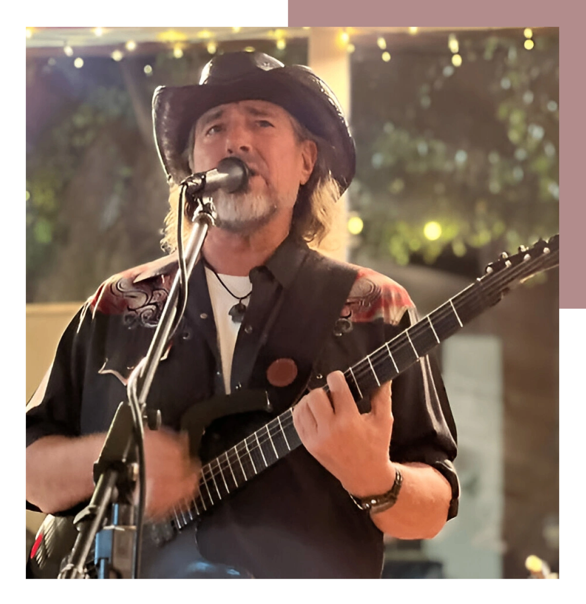 Musician passionately singing and playing guitar on stage.