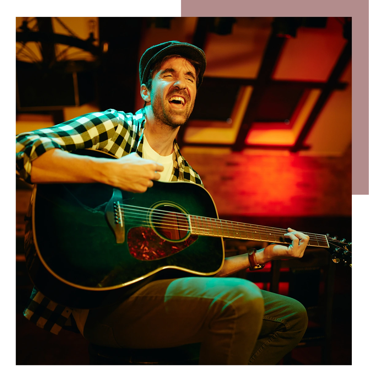 Man playing acoustic guitar on stage with expressive singing.